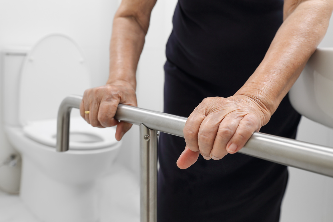 Elderly Holding onto a Railing Support in the Toilet 